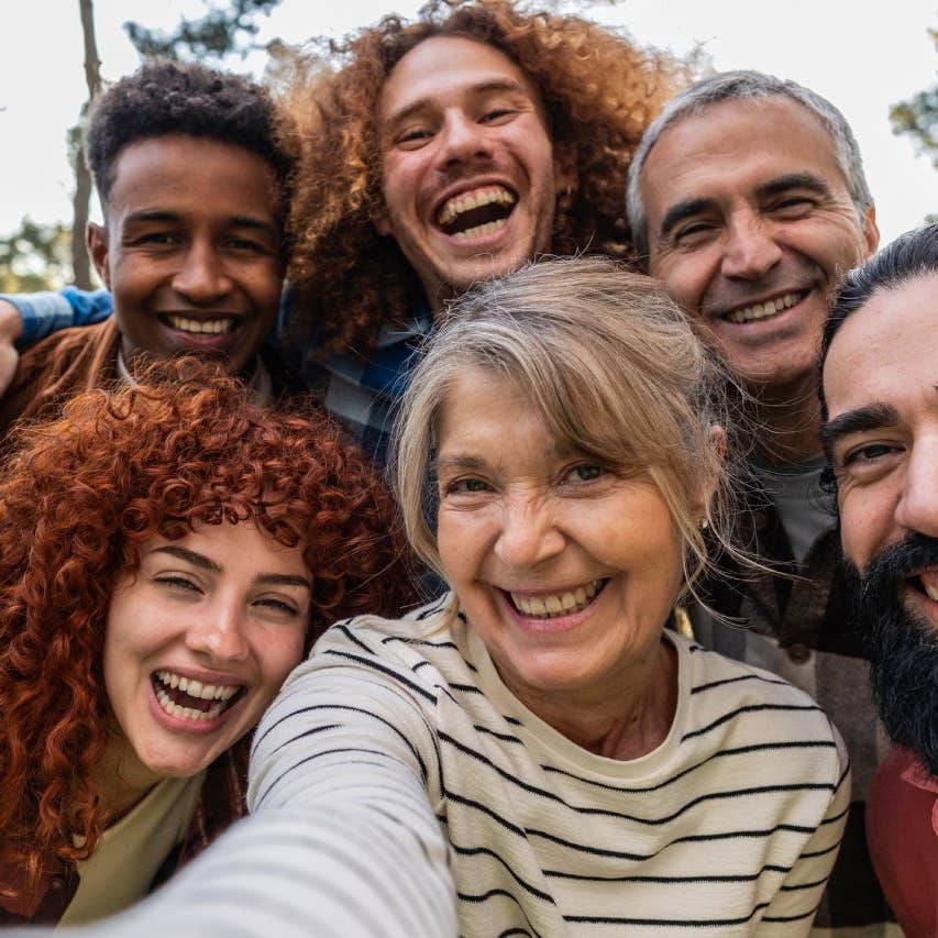 Group of cheerful, multi-ethnic friends spanning various ages enjoying a fun outdoor selfie, smiling and sharing joyful moments together in a lively park setting